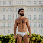Man in Caio bikini swim brief standing in front of the Copacabana Palace hotel.